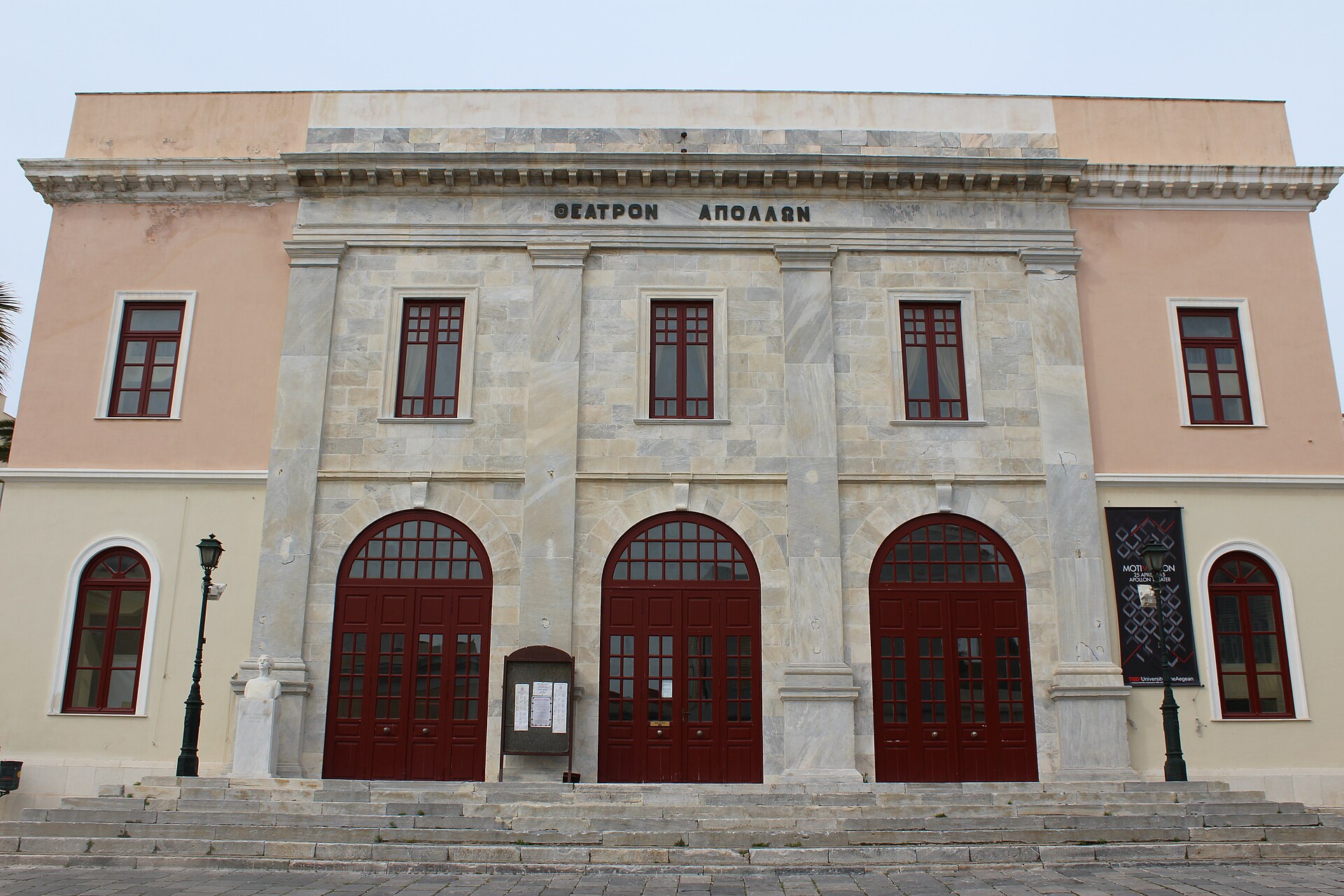 La facciata del Teatro Apollon a Ermoupoli, con porte rosse e il nome greco in alto