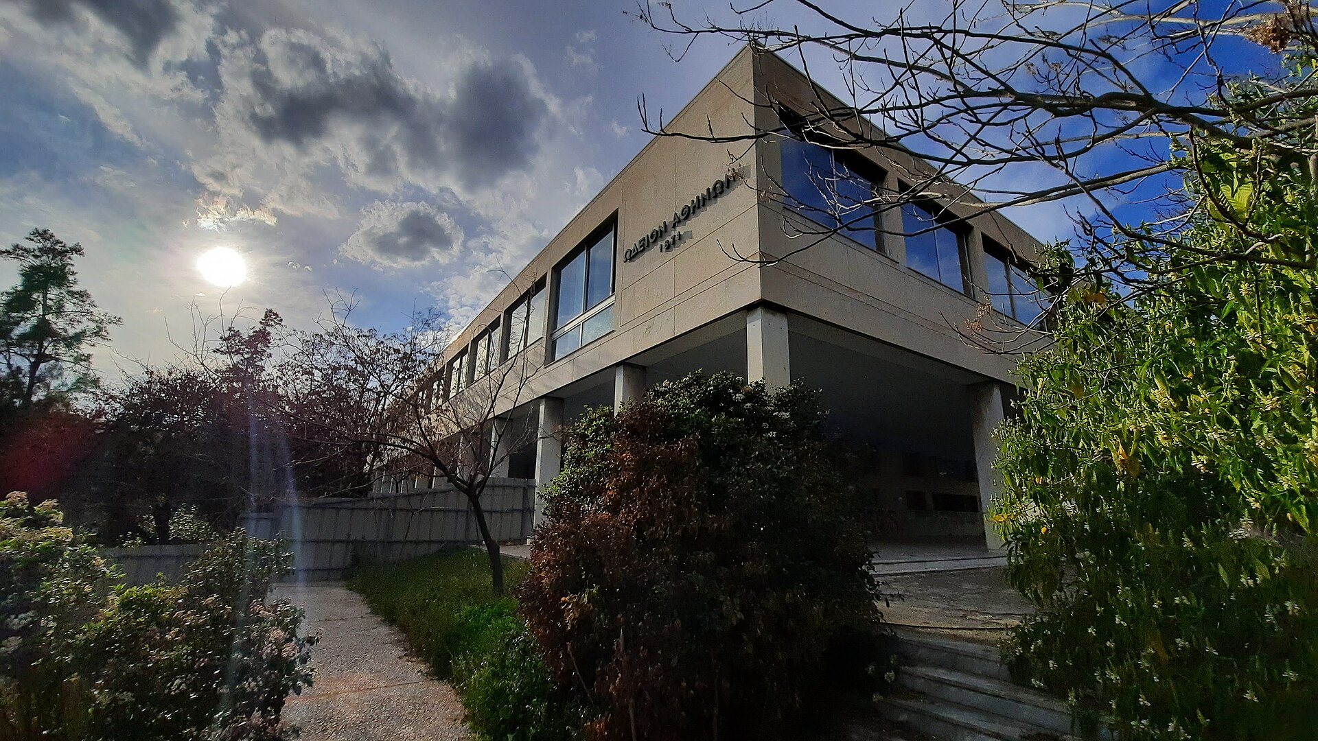 Una vista d’angolo dell’edificio modernista del Conservatorio di Atene, incorniciato dagli alberi