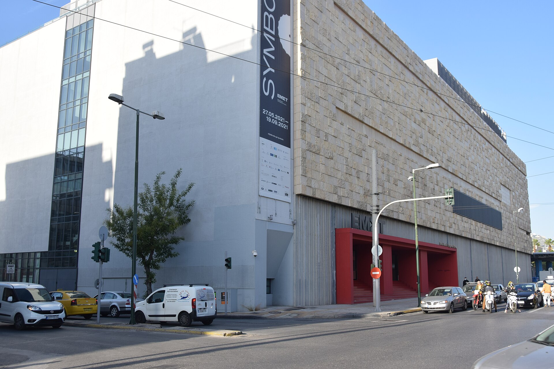La façade en marbre et l’entrée rouge de l’EMST, avec la circulation urbaine au premier plan