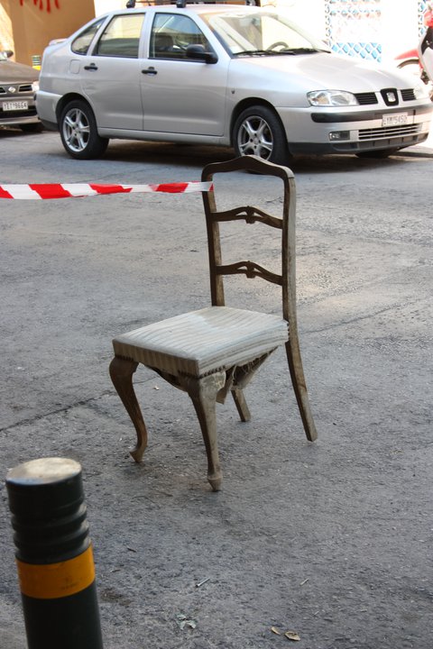 Atina’nın Metaksurgio semtinde bir sokakta bariyer şeridinin yanındaki eski ahşap sandalye